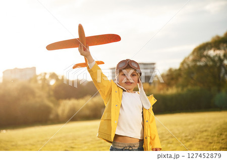 Retro style aviator glasses. Little boy is playing with toy plane on the summer field 127452879
