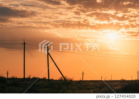 Sunset sky with power lines stretching over a desert landscape. Sunset sky with power lines stretching over a desert landscape. 127454020