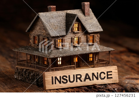 A detailed miniature wooden house is showcased on a rustic surface with warm lights glowing from its windows. 127456231