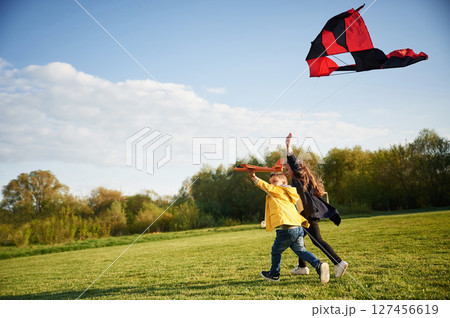 Clear sky. Two kids are playing with kite on the summer field 127456619