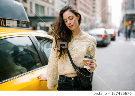A woman in a yellow sweater is holding a coffee cup A woman in a yellow sweater is holding a coffee cup 127456676