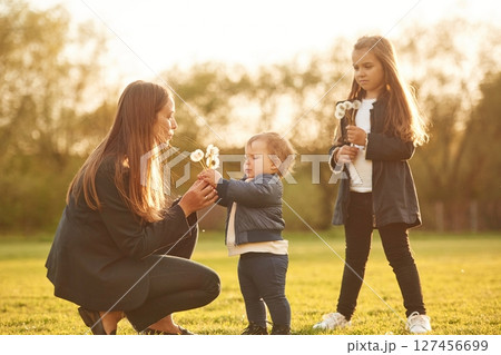 Playing with dandelion. Woman with her two young daughters is on the summer field 127456699