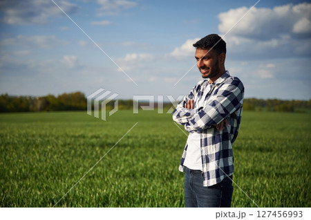 Standing with arms crossed. Handsome Indian man is on the agricultural field Standing with arms crossed. Handsome Indian man is on the agricultural field 127456993