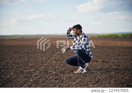 Digital tablet in hands. On cultivated agricultural field. Handsome Indian man Digital tablet in hands. On cultivated agricultural field. Handsome Indian man 127457005