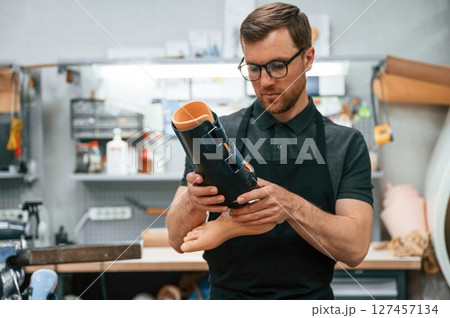 Holding prosthesis. Technician working in modern laboratory Holding prosthesis. Technician working in modern laboratory 127457134