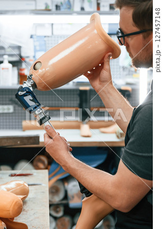 Checking the movement ability of product. Technician working with prosthesis in modern laboratory Checking the movement ability of product. Technician working with prosthesis in modern laboratory 127457148