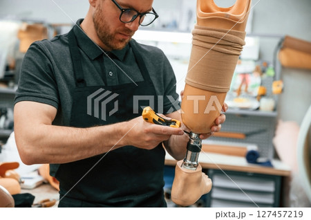 Tightening the screws. Technician working with prosthesis in modern laboratory 127457219