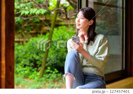 室内でスマートフォンを見ながら微笑む女性が過ごすリラックスした昼下がり 室内でスマートフォンを見ながら微笑む女性が過ごすリラックスした昼下がり 127457401
