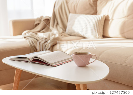 Cozy living room with a book and tea on a beige couch. Soft focus 127457509
