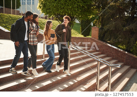 Four young students in casual clothes are together outdoors Four young students in casual clothes are together outdoors 127457553