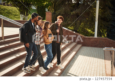 Four young students in casual clothes are together outdoors 127457554