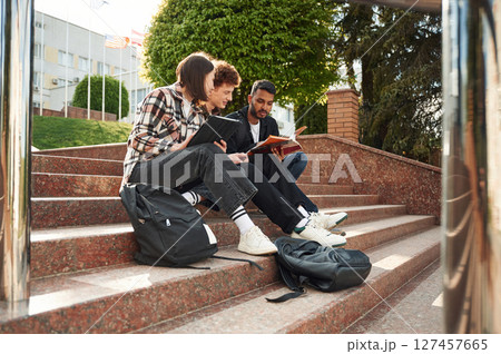 University building is behind. Young students in casual clothes are together outdoors 127457665