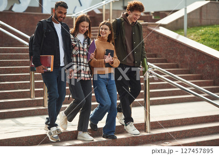 Hanging out after lessons. Four young students in casual clothes are together outdoors 127457895