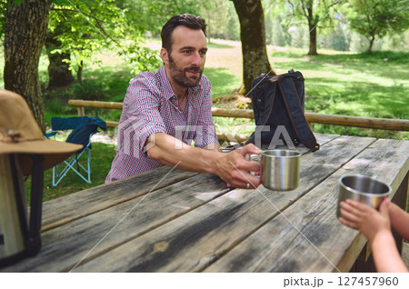 Man Sharing a Drink Outdoors in a Scenic Forest Setting Man Sharing a Drink Outdoors in a Scenic Forest Setting 127457960