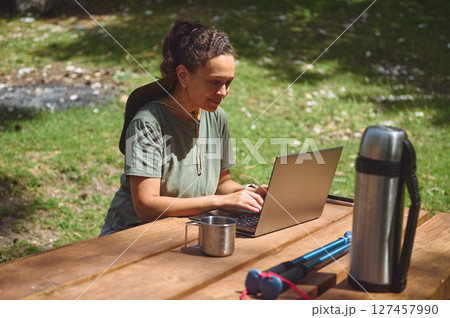 Young Woman Working Remotely Outdoors in a Natural Park Setting 127457990