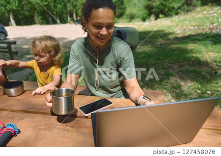 Woman Working Remotely in Nature While Caring for Child 127458076