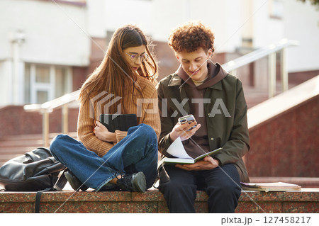 Man and woman students are together outdoors near university 127458217