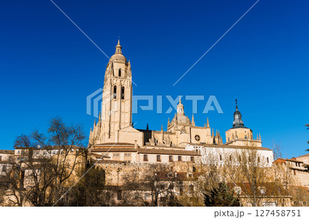 The Segovia Cathedral towers over the city under a clear blue sky near the Guadarrama mountains. The Segovia Cathedral towers over the city under a clear blue sky near the Guadarrama mountains. 127458751