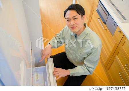 冷蔵庫を点検する作業服の日本人男性 冷蔵庫を点検する作業服の日本人男性 127458773