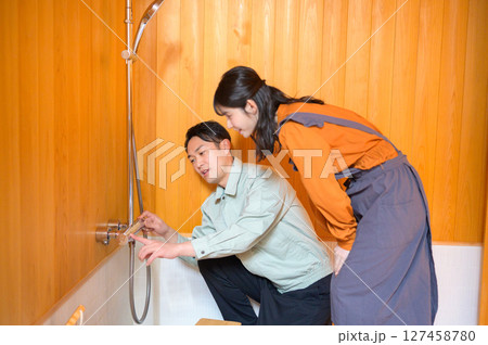 風呂場で水回りの点検をする日本人男性と見守る女性 風呂場で水回りの点検をする日本人男性と見守る女性 127458780