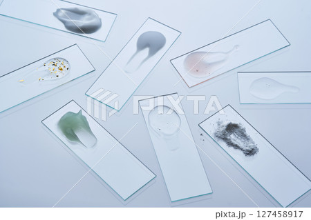 Various cosmetic products on slides on a dark gray background. 127458917
