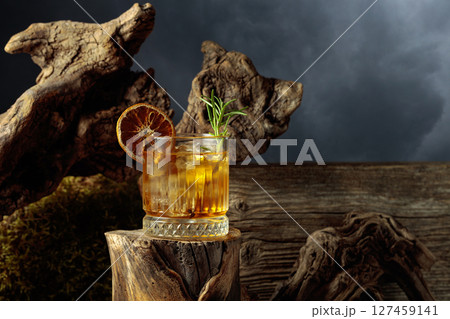 Old-fashioned cocktail with ice on an old wooden stump. Old-fashioned cocktail with ice on an old wooden stump. 127459141