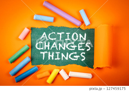 ACTION CHANGES THINGS Concept with Torn Paper and Colorful Chalk on Orange Background 127459175