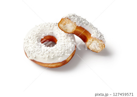 Two glazed donuts with white sprinkles, one showing cream filling on white background 127459571