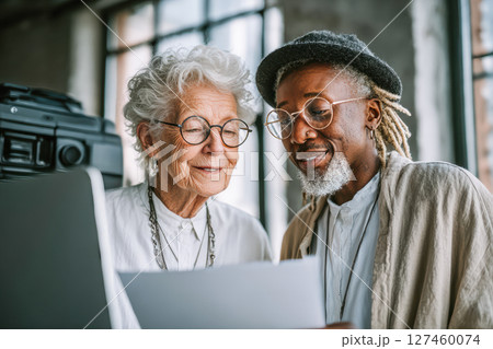 Senior couple reviewing documents together in a bright workspace with modern design elements Senior couple reviewing documents together in a bright workspace with modern design elements 127460074