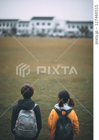 Children on a Grassy Field Facing Historic Buildings During a Cloudy Afternoon. 127460515