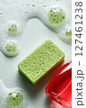 Cleaning Supplies Arranged With a Green Sponge and Soap Bubbles in a Bright Kitchen Setting 127461238