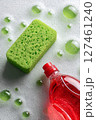 Cleaning Supplies Arranged With a Green Sponge and Soap Bubbles in a Bright Kitchen Setting. 127461240