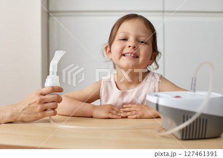 mother makes inhalation to cute toddler child girl at home 127461391