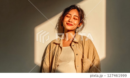 Pregnant woman smiling in soft sunlight with warm shadows creating a serene atmosphere Pregnant woman smiling in soft sunlight with warm shadows creating a serene atmosphere 127461999
