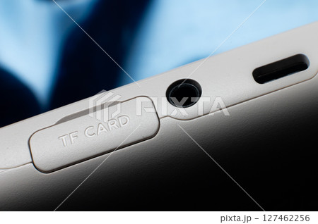 Close-up macro shot of the side panel of an electronic device, phone or portable gaming console. SD memory card slot with a protective cover and two mini-jack audio and type C connectors for charging Close-up macro shot of the side panel of an electronic device, phone or portable gaming console. SD memory card slot with a protective cover and two mini-jack audio and type C connectors for charging 127462256
