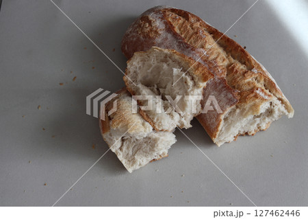 A broken freshly baked rustic baguette. 127462446