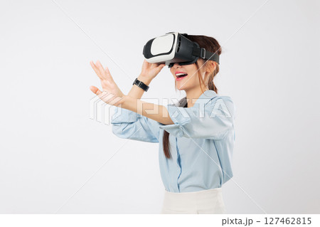 VR headset virtual reality for Asian woman in glasses game future; happy girl touches screen, interacts in virtual world, enjoying vr experience, and online app, isolated studio white background VR headset virtual reality for Asian woman in glasses game future; happy girl touches screen, interacts in virtual world, enjoying vr experience, and online app, isolated studio white background 127462815