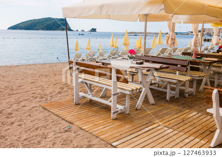 Outdoor cafe or restaurant with sea view and empty chairs. Coastal relaxation, summer tourism, and beachfront dining in the Mediterranean region. Outdoor cafe or restaurant with sea view and empty chairs. Coastal relaxation, summer tourism, and beachfront dining in the Mediterranean region. 127463933