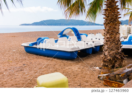 Blue and white pedal boats on shore. Summer recreation, water sports, and tourism infrastructure close-up 127463960
