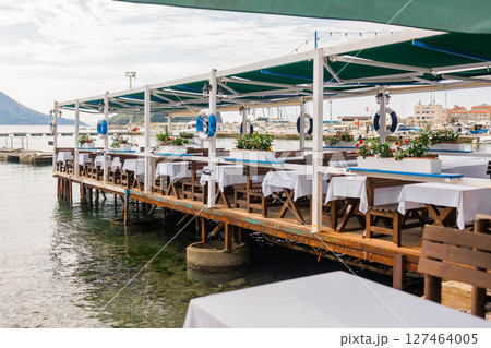 Outdoor cafe or restaurant with sea view and empty chairs. Coastal relaxation, summer tourism, and beachfront dining in the Mediterranean region. Outdoor cafe or restaurant with sea view and empty chairs. Coastal relaxation, summer tourism, and beachfront dining in the Mediterranean region. 127464005