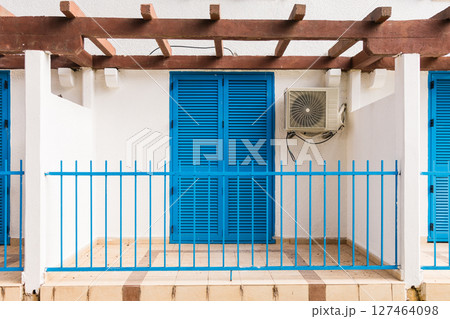 Mediterranean house with blue shutters behind pine trees. Relaxation, seaside living, and Mediterranean charm in a peaceful green environment. Mediterranean house with blue shutters behind pine trees. Relaxation, seaside living, and Mediterranean charm in a peaceful green environment. 127464098