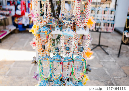 Colorful bead necklaces on tourist souvenir display. Summer travel, local craftsmanship, and coastal marketplace culture in Mediterranean street shops. Colorful bead necklaces on tourist souvenir display. Summer travel, local craftsmanship, and coastal marketplace culture in Mediterranean street shops. 127464118