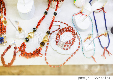 Red coral necklaces displayed on white showcase. Traditional jewelry, handcrafted coastal accessories, and natural gemstone aesthetics highlight regional artisanal heritage. 127464123