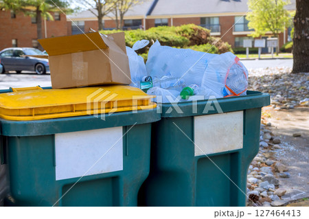 Town waste bins overflowing with garbage during works day in residential area 127464413