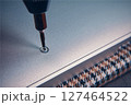 A close-up view of a screwdriver inserting a screw into a metallic surface, showcasing precision work. 127464522