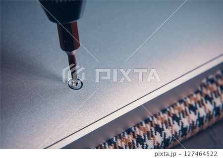 A close-up view of a screwdriver inserting a screw into a metallic surface, showcasing precision work. 127464522