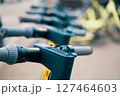 A row of electric scooters lined up on the street, showcasing their sleek metal frames and electric blue accents. The Bicycle handlebars and engineering design indicate a modern Machine construction 127464603