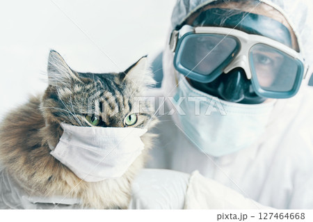 A person and a cat are both wearing masks in a photo, highlighting the importance of pandemic safety and care 127464668