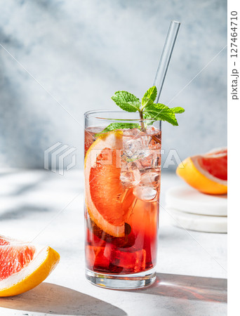 Refreshing cocktail with grapefruit, mint and ice in a glass on a light textured background Refreshing cocktail with grapefruit, mint and ice in a glass on a light textured background 127464710