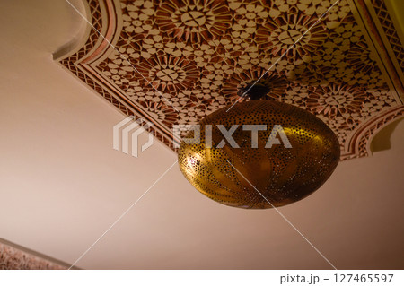 Typical Arabic lamp from Marrakech hanging with symmetrical patterns on ceiling 127465597